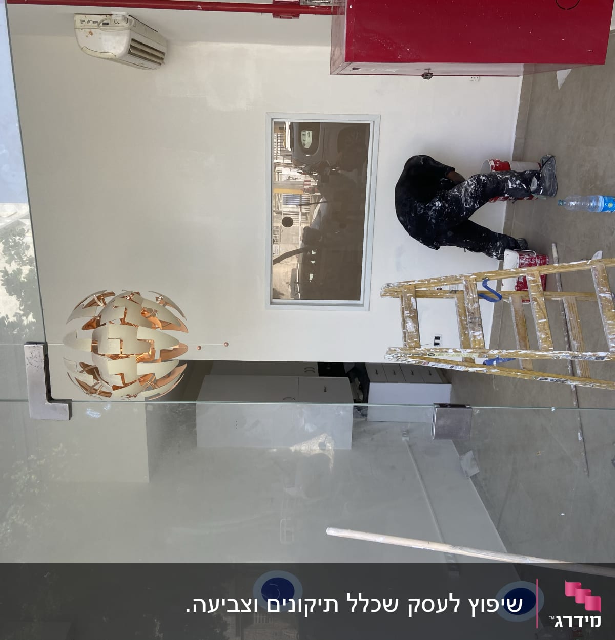 אדם צובע קיר עם סולם וכלי צבע